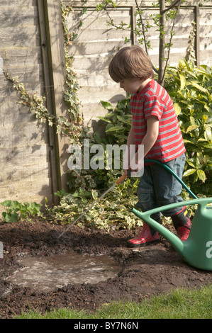 Garçon jouant avec le soutien de faire une flaque d'eau et de boue dans le jardin arrière. quatre-année-vieux Banque D'Images