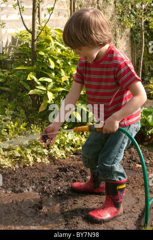 Garçon jouant avec le soutien de faire une flaque d'eau et de boue dans le jardin arrière. quatre-année-vieux Banque D'Images