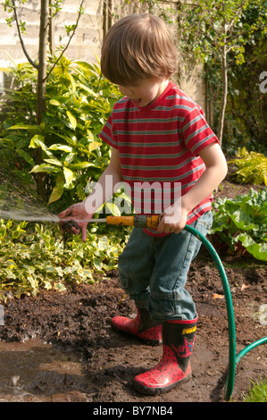 Garçon jouant avec le soutien de faire une flaque d'eau et de boue dans le jardin arrière. quatre-année-vieux Banque D'Images