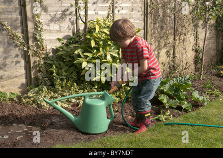 Garçon jouant avec le soutien de faire une flaque d'eau et de boue dans le jardin arrière. quatre-année-vieux Banque D'Images