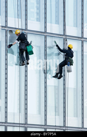 Deux laveurs de vitres sur des cordes suspendues, nettoyer les fenêtres de la BBC Ecosse bureaux, Pacific Quay, Glasgow, Ecosse, Royaume-Uni. Banque D'Images