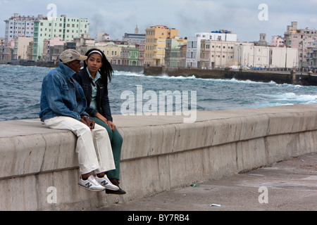 Cuba, La Havane. Un couple en conversation sur le Malecon sur une journée d'hiver. Banque D'Images