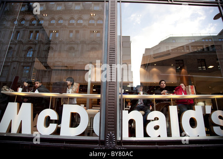 Les gens de manger dans la fenêtre de McDonald's à Leicester Square, Londres. Banque D'Images