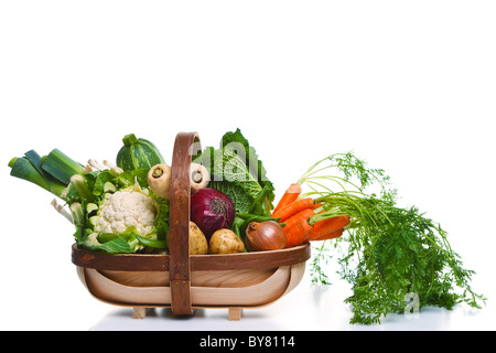 Photo d'un trug en bois plein de légumes bio, isolé sur un fond blanc. Banque D'Images