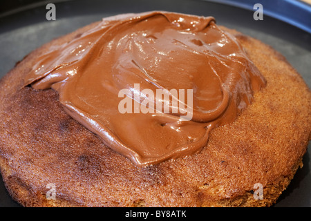 La diffusion de couverture de chocolat sur un gâteau au chocolat maison Banque D'Images