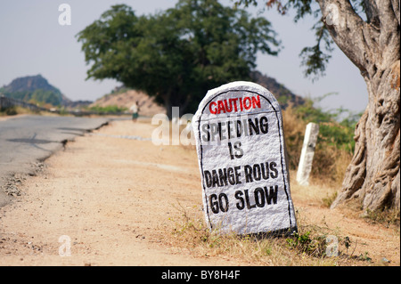 Sécurité routière du sud de l'Inde signe accélération peint sur une pierre au bord de la route. L'Andhra Pradesh, Inde Banque D'Images