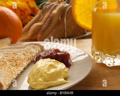 Petit-déjeuner avec du pain grillé, beurre, confiture et jus d'Orange Banque D'Images