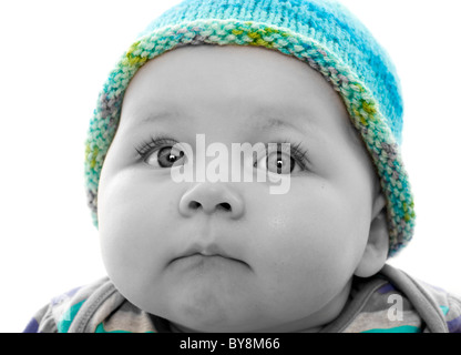 Photo à la tête monochrome de couleur à pois d'un bébé portant un chapeau tricoté turquoise, en regardant hors de la vue Banque D'Images