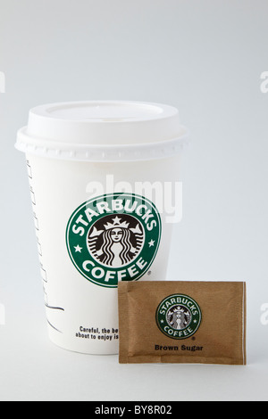 Des plats à emporter Starbucks Coffee cup en papier jetables en plastique pour emporter avec verre-grâce à couvercle et un sachet de sucre brun. Angleterre Royaume-uni Grande-Bretagne Banque D'Images