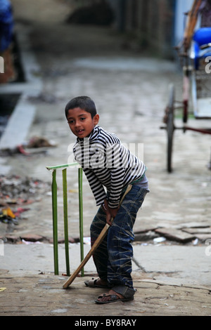 Kid jouer au cricket dans une petite rue de l'Afrique au Bangladesh Banque D'Images