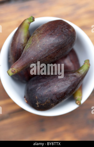 Figues dans un petit bol blanc sur la table en bois Banque D'Images