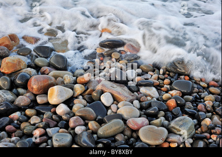 L'eau colorée cailloux lissés en surf à plage de galets Banque D'Images