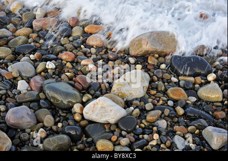 L'eau colorée cailloux lissés en surf à plage de galets Banque D'Images