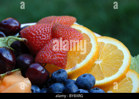 Arrangement de fruits avec des fraises, des bleuets, des tranches d'orange et des cerises Banque D'Images