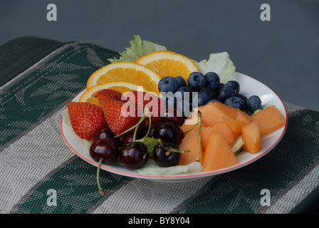 Bol de fruits avec des bleuets, fraises, oranges, cerises et melon. Les oranges sont tranchés et le cantaloup est coupé. Banque D'Images