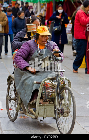 Les femmes tibétaines vieux pèlerin en fauteuil tricycle dans le Barkhor, Lhassa, Tibet. JMH4489 Banque D'Images