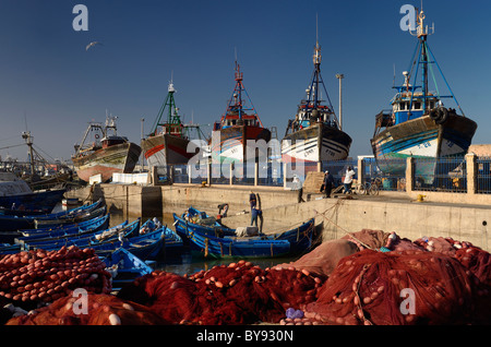 Filets rouge et gros bateaux de pêche et pêcheurs prêt à naviguer le matin au port d'Essaouira Maroc Banque D'Images