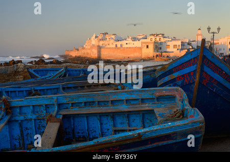 Des bateaux de pêche et de bleu océan Atlantique surf avec les remparts d'essaouira maroc au coucher du soleil Banque D'Images