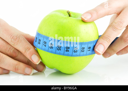 Woman's hands holding apple vert vif et isolé de ruban à mesurer Banque D'Images