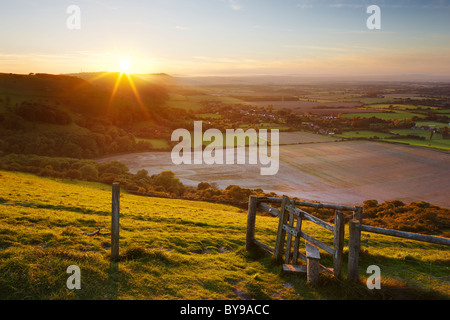 Stile avec vues sur la campagne du Sussex de l'Ouest. Le soleil du soir faisant sa descente derrière les collines ondulantes. Banque D'Images