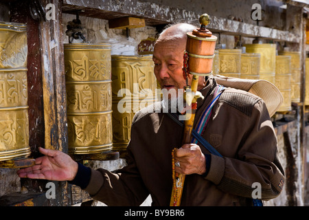 Pèlerin de tourner les roues de prière tibétain le long de la route au-dessous du Palais du Potala, Lhassa, Tibet. JMH4586 Banque D'Images