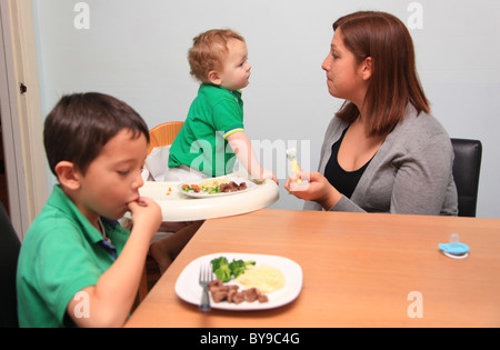 Mère célibataire à table avec ses deux jeunes fils. Banque D'Images