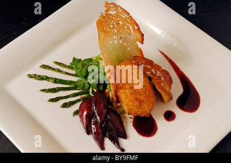 Foie de Canard rôti au four avec des oeufs pochés, des asperges sauvages et l'oignon rouge confit servi sur une plaque blanche, de l'alimentation, haute cuisine Banque D'Images