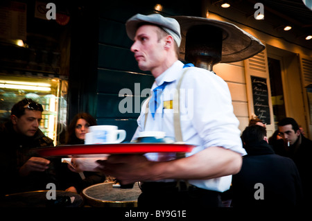 Serveur au travail, habillé sur une tradition d'attente, le service sur un café-terrasse du restaurant de Montmartre - Paris, France Banque D'Images