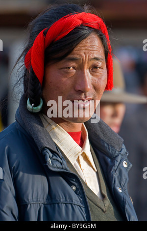 L'homme de la Tibétain Khampas région Kham portant robe tête rouge caractéristique de marcher dans le Barkhor, Lhassa, Tibet. JMH4631 Banque D'Images