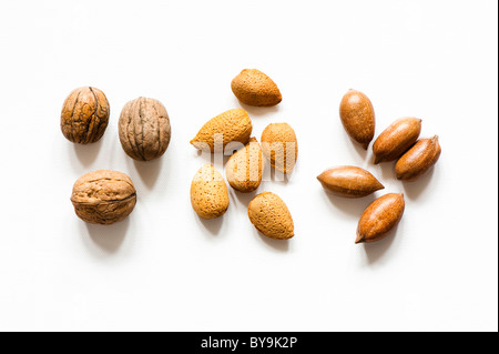 Trois noix, amandes et six cinq noix de pécan sur un fond blanc. Banque D'Images