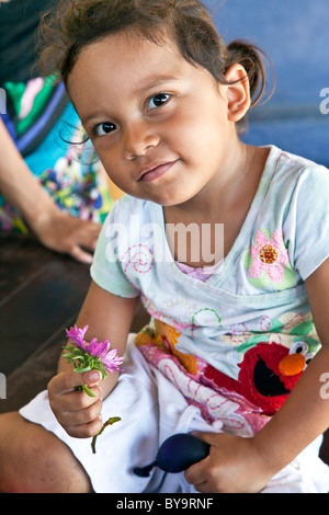 Dark eyed peu espiègle fille mexicaine en jolie fleur rose détient en t pour l'inspection de l'état d'Oaxaca au Mexique Puerto Angel Banque D'Images