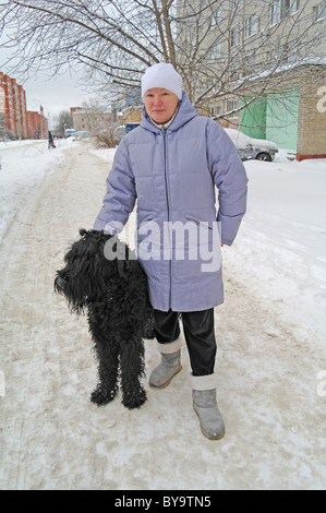 Chien Terrier Noir Russe avec la maîtresse dans la rue, l'hiver dans la région de Moscou, Russie Banque D'Images