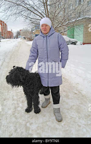 Chien Terrier Noir Russe avec la maîtresse dans la rue, l'hiver dans la région de Moscou, Russie Banque D'Images