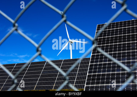 Des panneaux solaires et une éolienne derrière une clôture de sécurité maillé, solar power station Mont Soleil, Jura, Suisse Banque D'Images