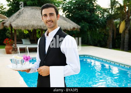 Hôtel waiter holding tray par piscine de l'hôtel Banque D'Images