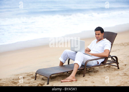 Homme avec un ordinateur portable sur une plage