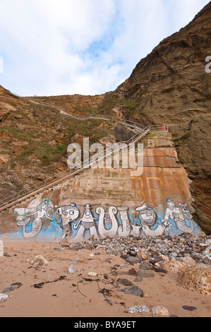 Les étapes qui mènent à la plage de Whipsiderry, Newquay, avec un graffittied mur en dessous. Banque D'Images