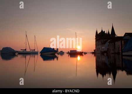 Turmhof bâtiment dans Geräte-service sur le lac de Constance au lever du soleil avec des bateaux sur les bouées et les reflets dans l'eau, la Suisse, l'Europe Banque D'Images