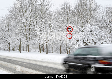 Voiture sur une route couverte de neige en hiver, le risque de glisser, avertissement, signe d'interdiction, flou Banque D'Images