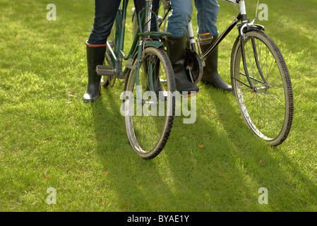 Close-up, deux personnes + herbe vieilles bicyclettes Banque D'Images
