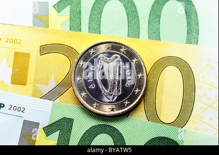 Un irlandais pièce en euros sur les billets en euros, image symbolique pour le financement de l'UE pour l'Irlande Banque D'Images