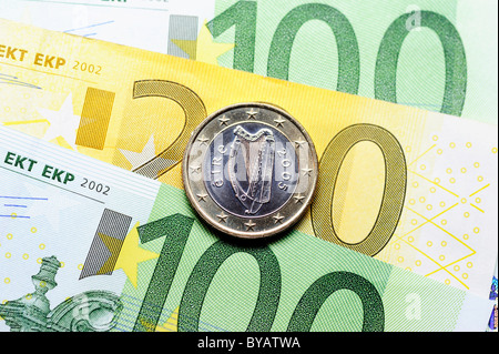 Un irlandais pièce en euros sur les billets en euros, image symbolique pour le financement de l'UE pour l'Irlande Banque D'Images