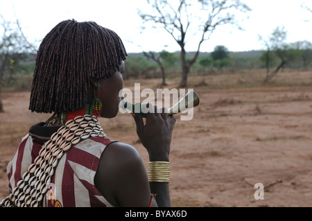 Jeune femme de la tribu Hamar soufflant une corne afin d'attirer l'attention au cours de la cérémonie, bull-sautant un rite d'initiation Banque D'Images