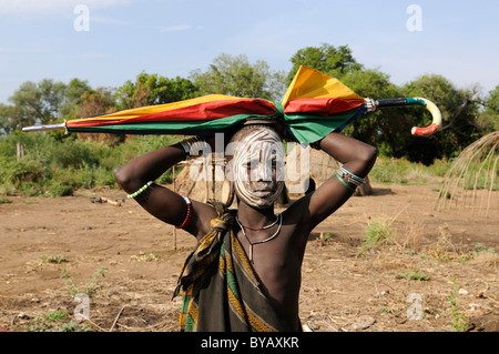 Jeune fille de la tribu Mursi avec parapluie sur la tête, Magon, Parc National de la vallée de l'Omo méridionale, au sud de l'Éthiopie, de l'Éthiopie Banque D'Images