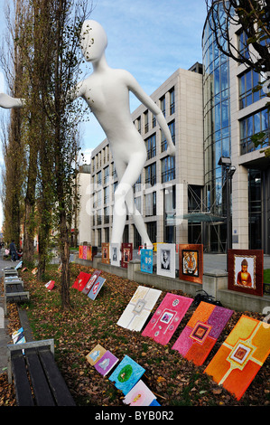 Peintures à vendre au pied de la statue de l'homme marche dans la rue Leopoldstrasse, Munich, Bavaria, Germany, Europe Banque D'Images