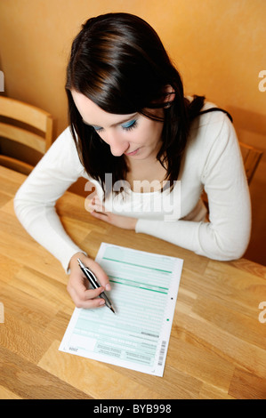 Jeune femme en train de remplir une déclaration de revenus Banque D'Images