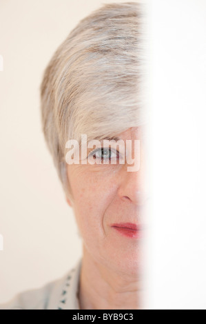 Woman, portrait, la moitié derrière une feuille de papier Banque D'Images