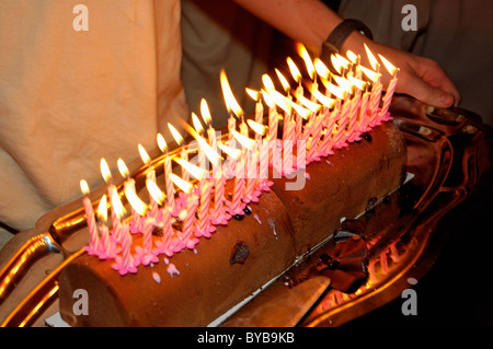 Homme portant un gâteau au chocolat très chargé avec quarante allumé des bougies d'anniversaire. Banque D'Images
