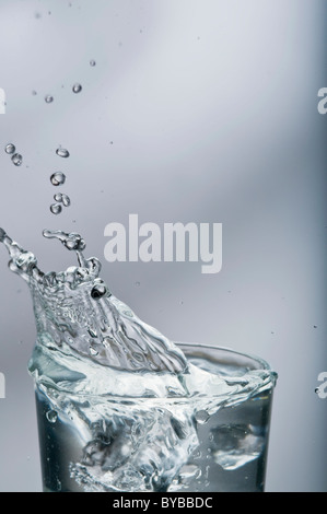 Une projection d'eau douce d'un verre avec des glaçons sur gradient background Banque D'Images