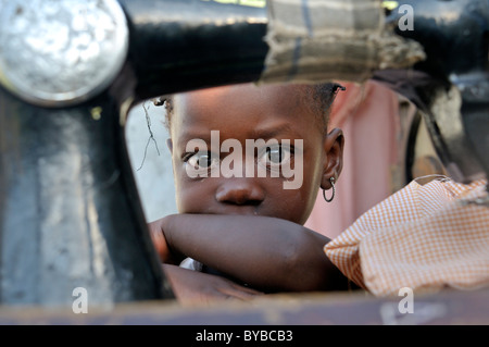 Petite fille se cacher derrière une vieille machine à coudre mécanique, camp pour les victimes de tremblement de terre de janvier 2010 Banque D'Images